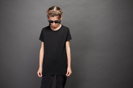 Kid girl wearing black t-shirt with space for your logo or design in studio over gray backgroundの写真素材