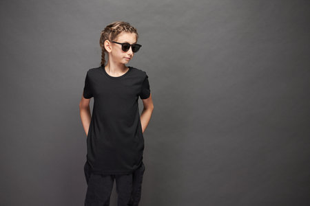 Kid girl wearing black t-shirt with space for your logo or design in studio over gray backgroundの写真素材