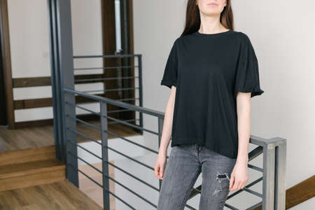 Woman wearing black blank t-shirt with space for your logo, mock up or design indoors