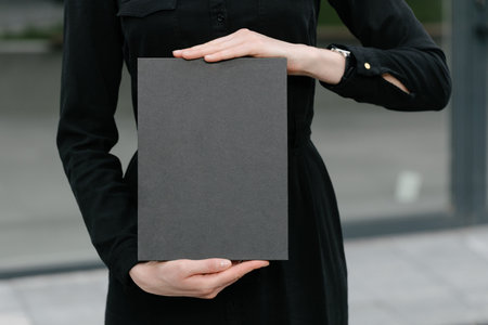 Black book cover in woman's hands. Book cover for mock upの写真素材