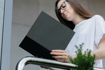 Black book cover in woman's hands. Book cover for mock upの写真素材