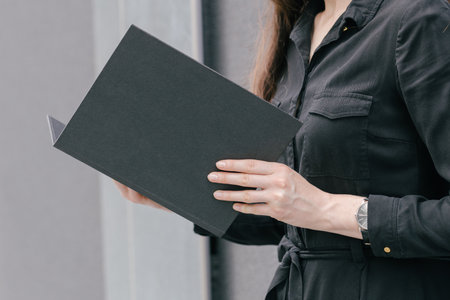 Black book cover in woman's hands. Book cover for mock upの写真素材