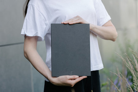 Black book cover in woman's hands. Book cover for mock upの写真素材
