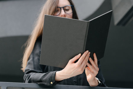 Black book cover in woman's hands. Book cover for mock upの写真素材