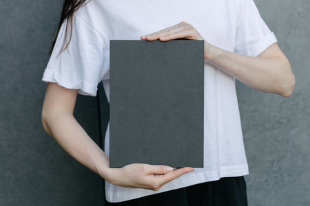 Black book cover in woman's hands. Book cover for mock upの写真素材