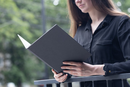 Black book cover in woman's hands. Book cover for mock upの写真素材