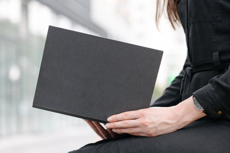 Black book cover in woman's hands. Book cover for mock upの写真素材