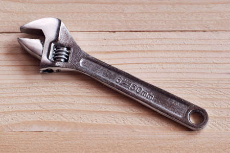 Chrome-plated adjustable wrench on a wooden backgroundの写真素材