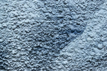 old rough surface of a concrete wall with an uneven coating of silver paint