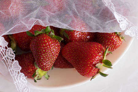 red strawberries, lying on a platter, covered with a covering materialの写真素材