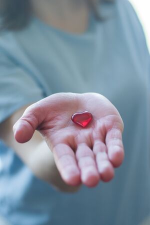 Women in a medical mask holds a heart in her handの写真素材