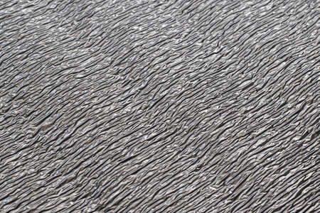 Metallized gray reflective coating of thermal insulation mat. background of crumpled metal surface with waves.の写真素材
