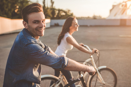Beautiful romantic couple is having rest in the city with bicycles on the sunset. Enjoying the company of each other.の写真素材