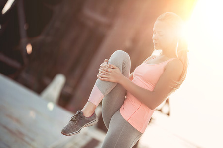 Attractive sporty girl is stretching on street during the sunsetの写真素材