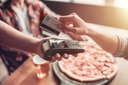 Cropped image of men paying via credit card in bar.の写真素材