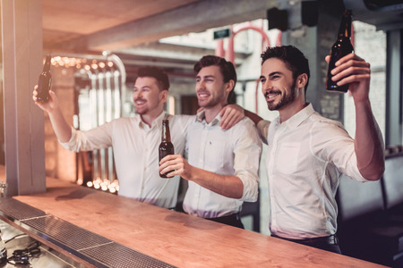 Young handsome fans in suits are drinking beer on a bar counterの写真素材