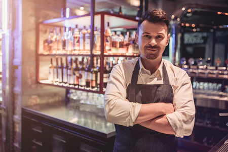 Cheerful bartender on a bar counter is working and smiling.の写真素材