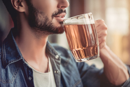 Cropped image of handsome young man is drinking beer in barの写真素材