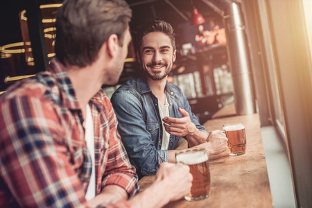 Meeting of two male friends in bar. Discussing the latest news and smilingの写真素材