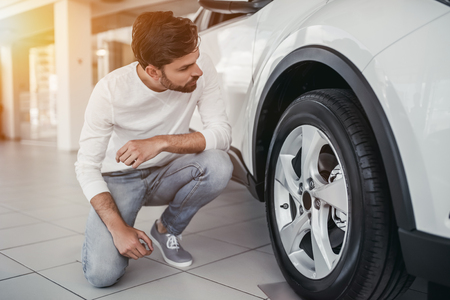 Young man is choosing a new vehicle in car dealership.の写真素材