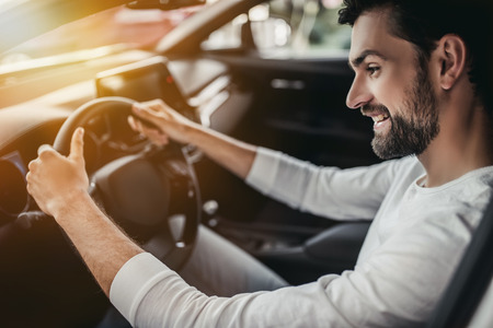 Young man is choosing a new vehicle in car dealership.の写真素材