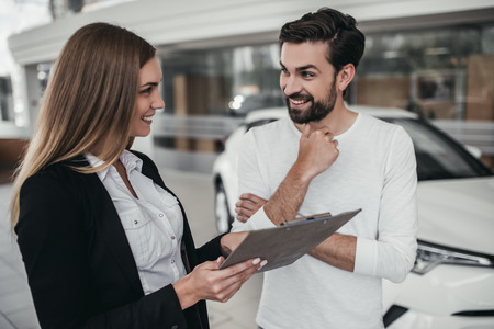 Professional salesperson during work with customer at car dealership.の写真素材
