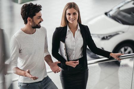 Professional salesperson during work with customer at car dealership.の写真素材