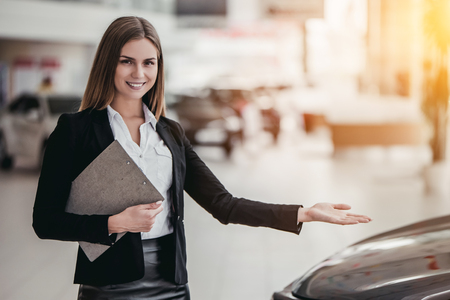 Professional female salesperson at car dealership.の写真素材