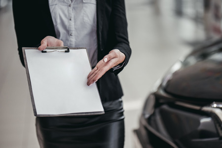 Cropped image of professional female salesperson at car dealership.の写真素材