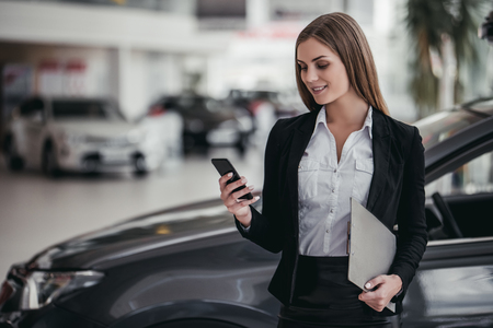 Professional female salesperson at car dealership.の写真素材