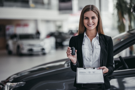 Professional female salesperson at car dealership.の写真素材