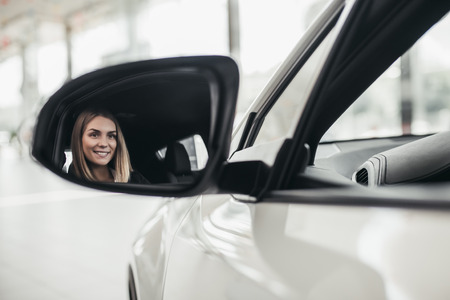 Attractive young businesswoman is choosing new vehicle in car dealership.の写真素材