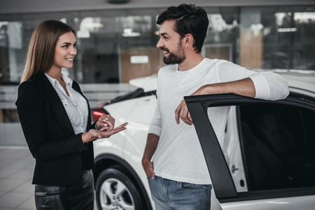 Professional salesperson during work with customer at car dealership. Naming all the benefits of new vehicle.の写真素材