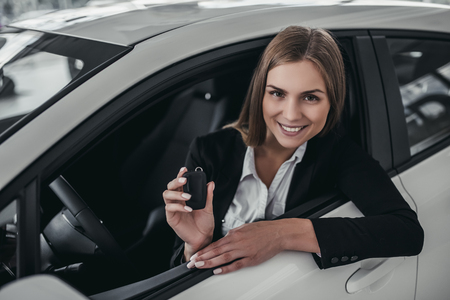 Attractive young businesswoman is choosing new vehicle in car dealership.の写真素材