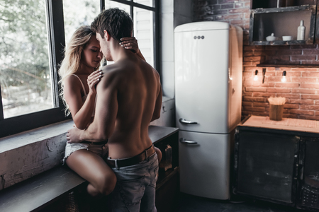 Attractive passionate couple on kitchen face to face.の写真素材