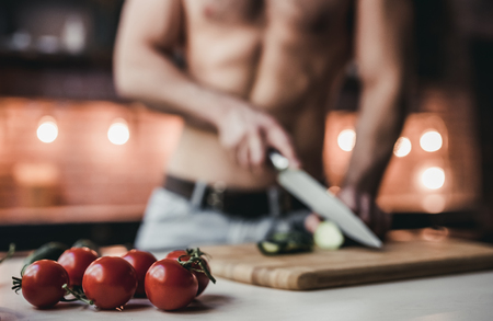 Cropped image of sporty topless man is cooking on kitchen.の写真素材