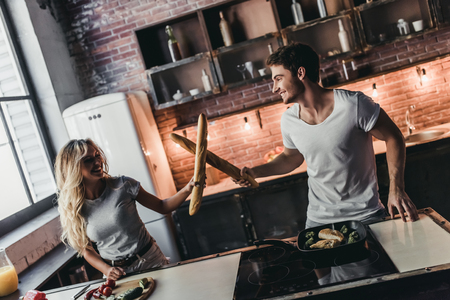 Attractive couple on kitchen having fun while cooking. Bread fight.の写真素材