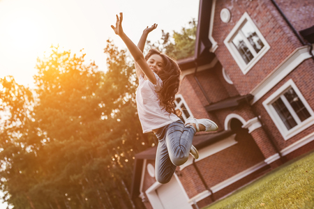 Pretty little girl is jumping and having fun on the backyard on the sunset.の写真素材