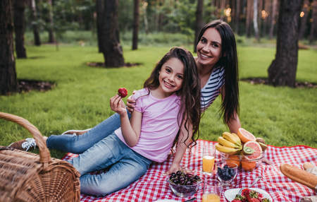 Beautiful young mom with daughter on a picnic. Smiling and looking at camera.の写真素材