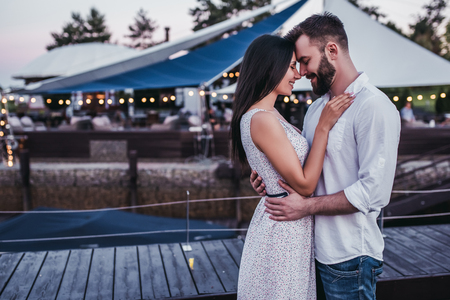Beautiful romantic couple on house's terrace. Hugging, smiling and enjoing the company of each other.の写真素材