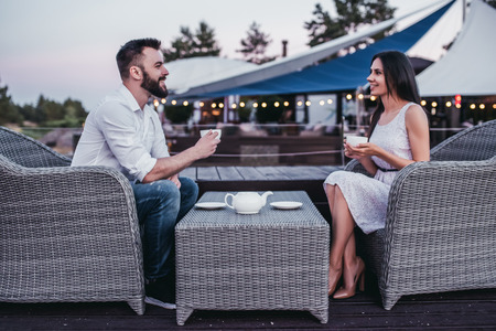 Beautiful couple is sitting in cafe, drinking tea and smilingの写真素材
