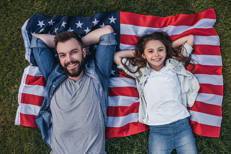 Top view of dad and daughter are lying on the american flag and smilingの写真素材