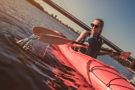 Attractive young woman is kayaking on sunset. Canoeing alone.の写真素材