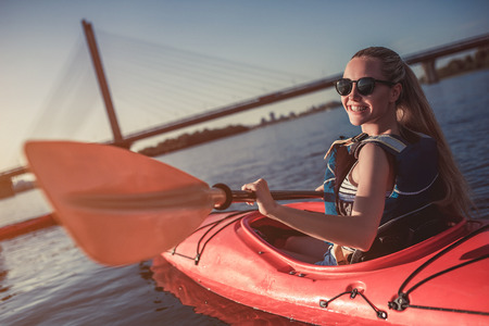Attractive young woman is kayaking on sunset. Canoeing alone.の写真素材