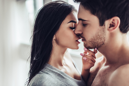 Close-up of young romantic couple is kissing and enjoying the company of each other at home.の写真素材