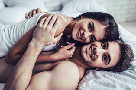 Happy couple is lying in bed together. Enjoying the company of each other.の写真素材
