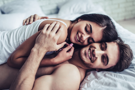 Happy couple is lying in bed together. Enjoying the company of each other.の写真素材
