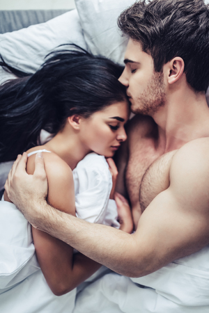 Close-up of happy couple is lying in bed together. Enjoying the company of each other.の写真素材