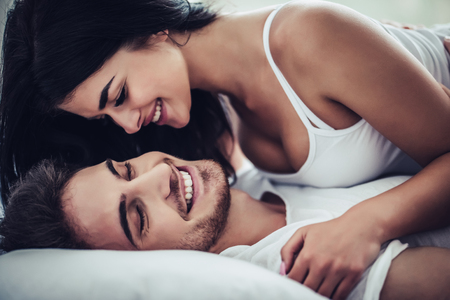 Happy couple is lying in bed together. Enjoying the company of each other.の写真素材
