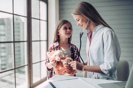 Little cute girl with plush toy at doctor pediatrician.の写真素材